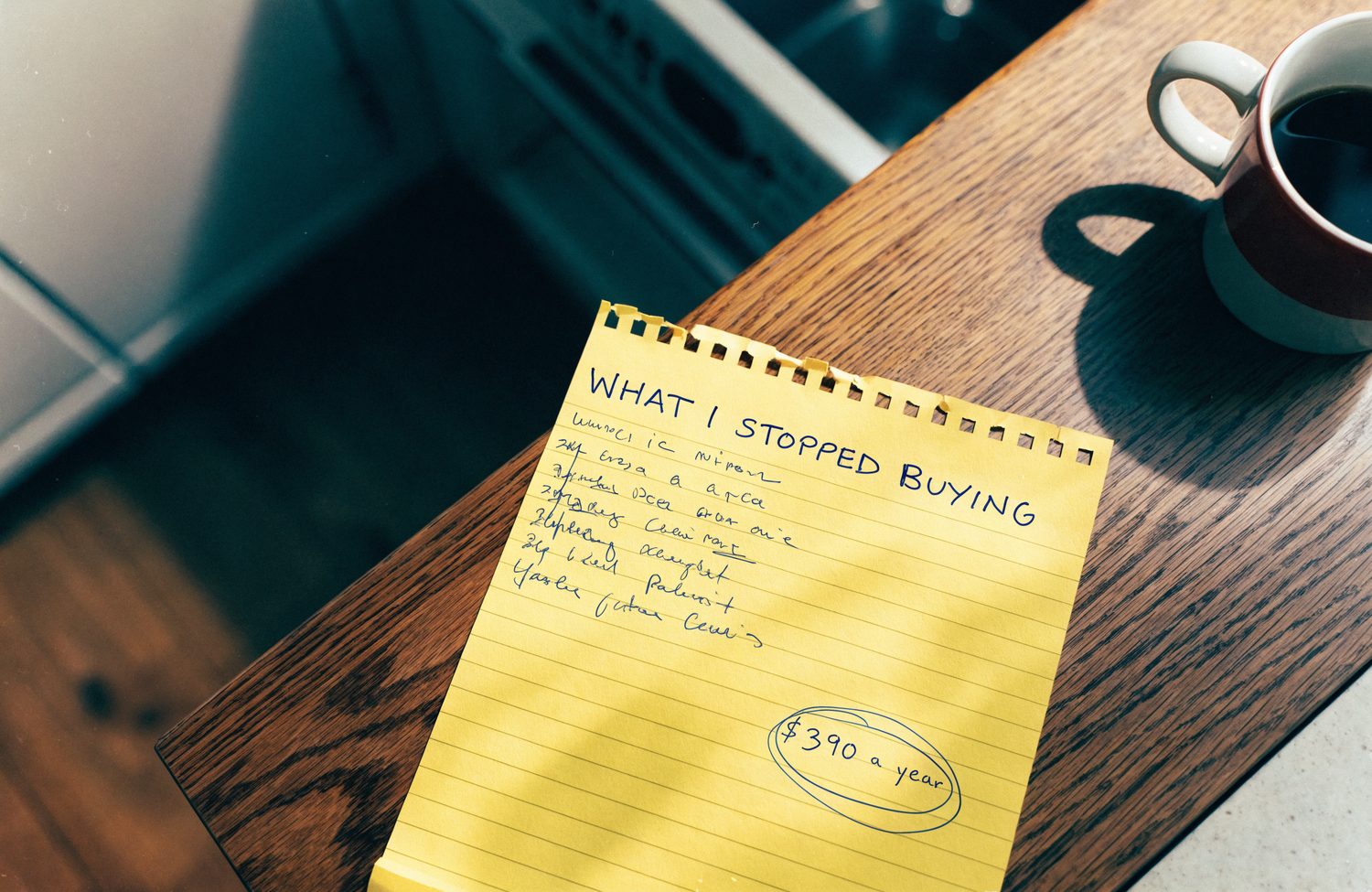 A yellow legal pad with a handwritten list headed 'What I stopped buying' and a dollar figure circled at the bottom.